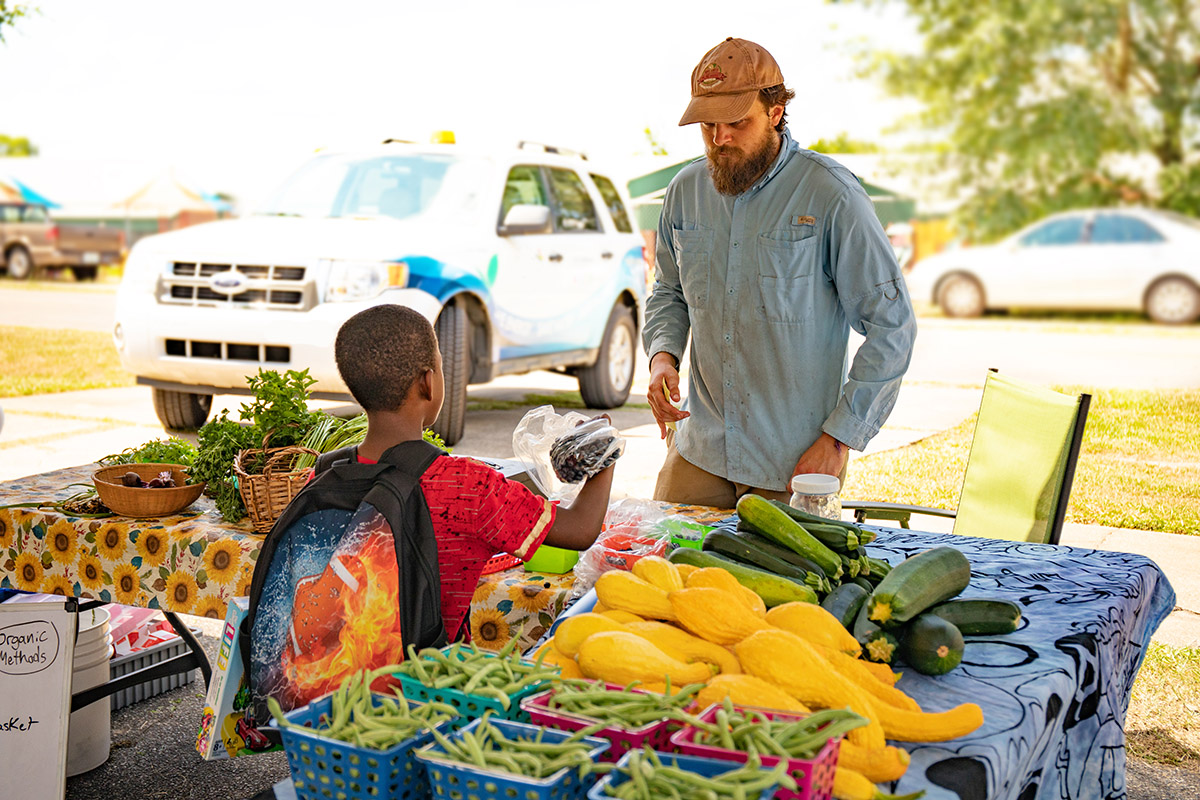 A vendor teaches kids how to plant seeds.