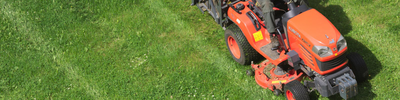 A riding lawn mower working in a field.