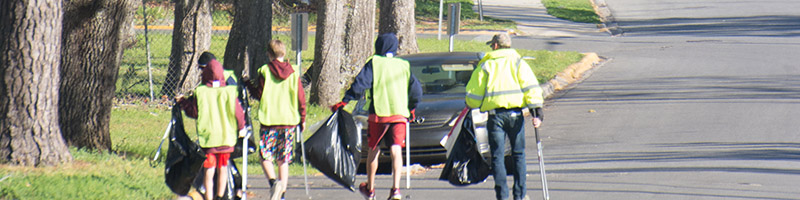 A group of people collect trash along a city street.